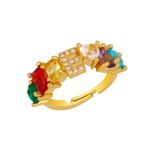 Close-up of gold adjustable ring featuring a diamond-set letter E and colorful gemstones