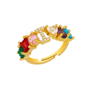 Detail of adjustable gold ring featuring letter L and colorful embedded gemstones