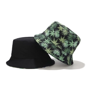Set of 2 reversible bucket hats with solid black and green leaf print patterns