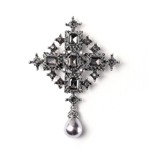 Vista detallada de un broche de cruz barroco vintage de diamantes de imitación con perlas.