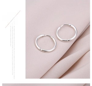 Detail van zilveren titanium stalen creolen met hoogglans afwerking op roze stof