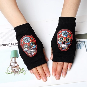 Detail der bunten Totenkopf-Stickerei auf schwarzen Strickhandschuhen ohne Fingerkuppen