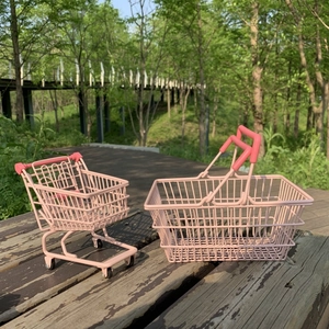 Pink iron mini shopping cart and hand basket organizers set on a rustic wooden bench