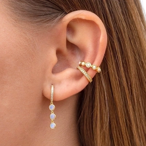 Elegant gold drop earrings with white pearls and sparkling crystals on female ear