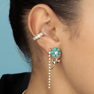 Floral earring with turquoise flower and diamond fringe tassel on model against blue sky