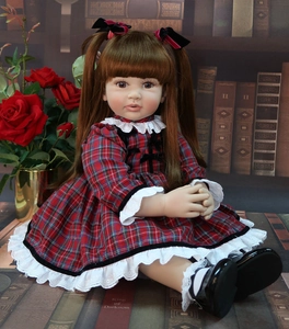 60cm reborn doll with brown pigtails in red plaid dress and black shoes in studio setting