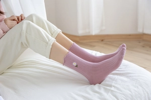 Detail of pink lavender ruffled socks featuring delicate daisy embroidery and ribbed cotton