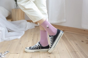 Detail of pink lavender mid-calf socks with lace trim and daisy embroidery on cotton