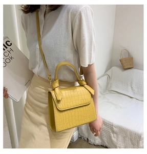 Close-up of yellow crocodile texture crossbody bag with gold hardware and flap closure