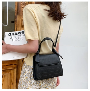 Rear view of a model wearing a black crocodile pattern crossbody bag with a floral skirt