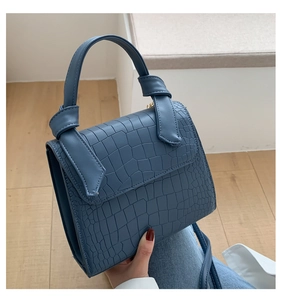 Detail of grey-blue faux crocodile texture handbag with unique knot handle design