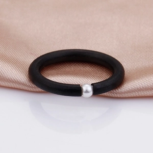 Minimalist matte black ring with a single white pearl accent on a satin background
