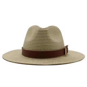 Detail of a natural beige straw hat featuring a brown leather band and gold square buckle