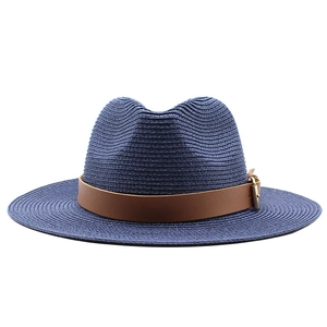 Detail of dark blue straw sun hat featuring a brown leather band and gold metal buckle