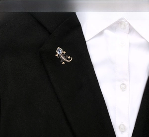 Lizard brooch in gold alloy with rhinestones pinned on a black suit lapel detail