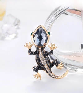 Detailed close-up of a lizard brooch featuring a grey gemstone head and black enamel body