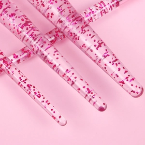 Close-up of pink liquid glitter handles for eye makeup and nail art brushes