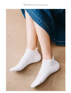 Close-up of white low-cut cotton socks with heel tab detail on wooden floor background