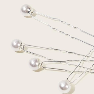 Detailed view of four elegant silver U-shaped hair pins with white faux pearls