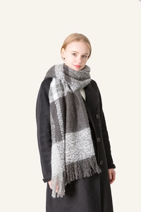 Close-up of gray and white plaid scarf with fringe tassels on a fashion model
