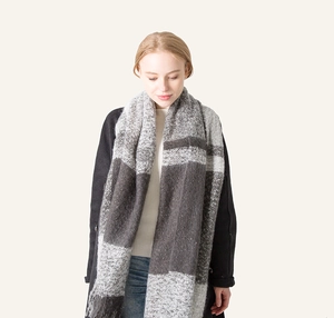 Detail shot of grey and white plaid scarf with fringe tassels on a fashion model