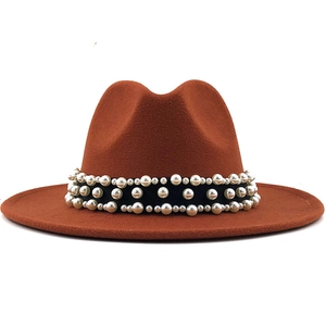 Detail of caramel fedora hat featuring a black ribbon band with rows of elegant white pearls