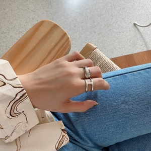 Close-up of minimalist silver 925 rings featuring a sleek wide band and a cutout H design
