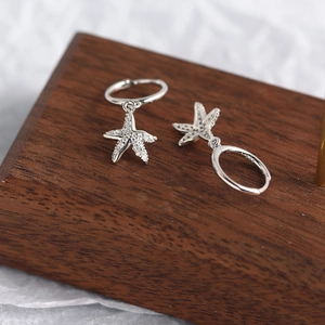 Close-up of S925 sterling silver starfish hoop earrings with zircon on wood block
