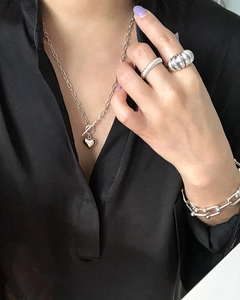 Close-up of S925 sterling silver heart necklace and metal rings on a black shirt