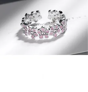 Macro shot of silver open ring with pink enamel flowers and metallic floral details