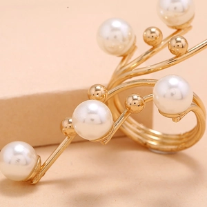 Macro view of gold flower-shaped ring featuring elegant white pearls on curved metal lines