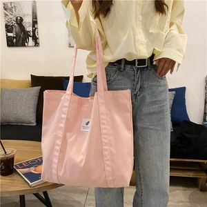Detailed shot of the pink canvas tote bag with a white square tag on the front pocket