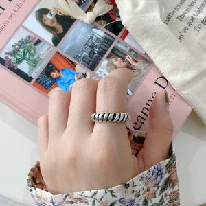 Detail of twisted silver rope ring worn on finger with vintage aesthetic lifestyle background