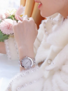 Detailed view of luxury silver watch with full diamond dial on a female model wrist