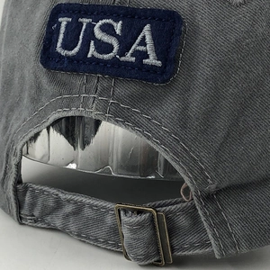 Macro detail of washed dark gray cotton baseball cap with USA embroidery and metal buckle