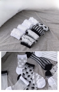 Detail of sheer mesh socks with heart prints, dots, and stripes on linen background