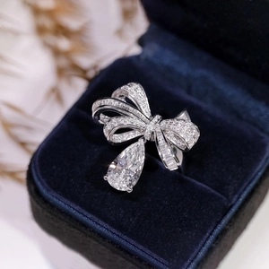 Macro view of bow ring with pear-cut drop diamond in a luxury blue velvet jewelry box