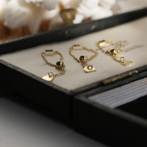 Adjustable gold chain rings featuring emerald and ruby-cut gems and heart charm
