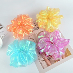 Set of four shimmering organza hair scrunchies in bright neon colors on a magazine background