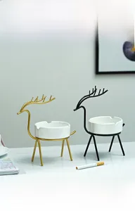 Détail du cendrier en céramique blanche avec supports en métal doré et noir en cerf