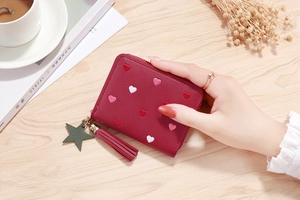 Detail of red PU leather wallet with heart embroidery, tassel and star charm