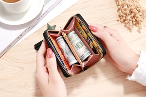 Detail of a compact accordion-style wallet with black PU leather and star tassel zipper
