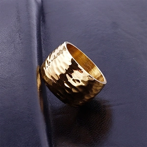 Polished golden stainless steel ring featuring a unique hammered texture on dark leather