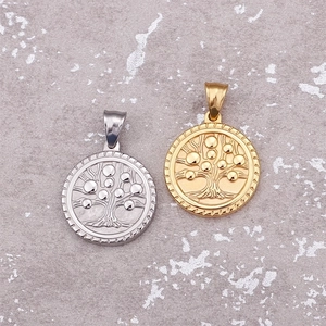 Gold and silver Tree of Life pendants in round titanium steel on a stone background