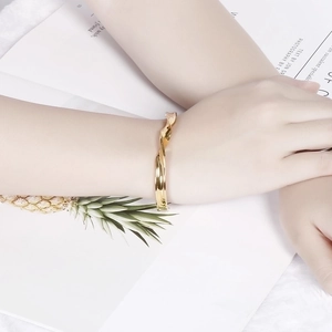Minimalist golden twisted open cuff bracelet for women in a stylish magazine lifestyle shot