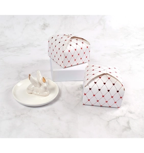 Close-up of white gift box with red heart diamond pattern on marble surface