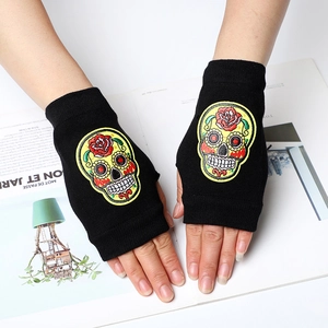 Black knitted fingerless gloves with colorful embroidered sugar skulls on white magazine