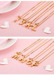 Detail of bamboo-textured gold letter pendants with zircon inlay on fine chains