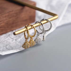 Detail view of gold and silver S925 sterling silver shell earrings with small diamonds