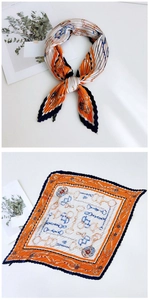Detail of pleated silk scarf featuring orange and navy chain and horsebit print